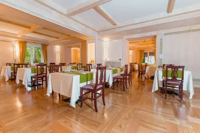 a dining room with white tables and chairs at Hotel Serena Cortina in Cortina dʼAmpezzo