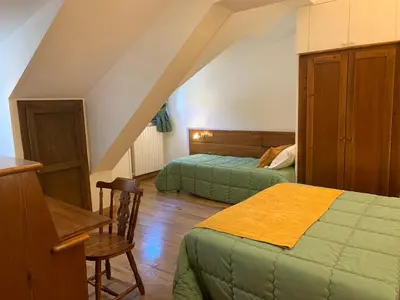a attic bedroom with two beds and a table and chair at Hotel Serena Cortina in Cortina dʼAmpezzo