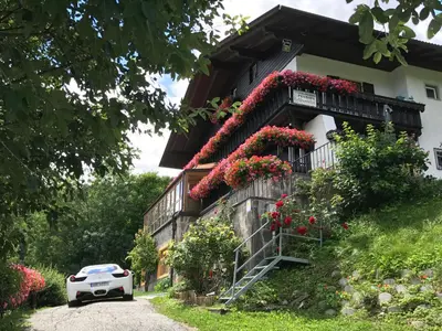 a white car parked in front of a house with flowers at Alpenblick Bed & Breakfast in Vipiteno
