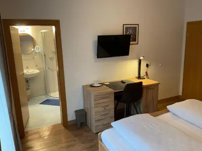 a bedroom with a desk and a bed and a bathroom at Alpenblick Bed & Breakfast in Vipiteno