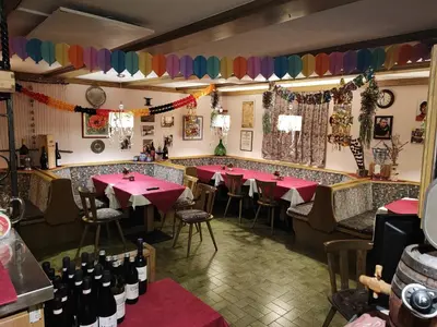 a restaurant with red tables and bottles of wine at Alpenblick Bed & Breakfast in Vipiteno