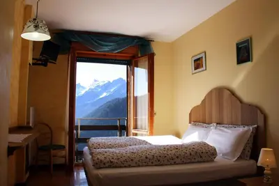 a house on a hill with a mountain in the background at HG Hotel La Caminatha in Val di Zoldo