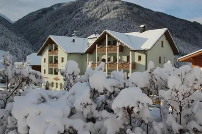 a house covered in snow in front of a mountain at Hotel Rosental in Luson