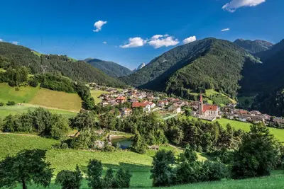 a village on a hill with mountains in the background at Hotel Rosental in Luson