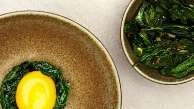 two bowls of greens and an egg on a table at Forestis Dolomites in Bressanone