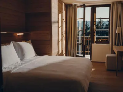 a bedroom with a white bed and a balcony at Forestis Dolomites in Bressanone