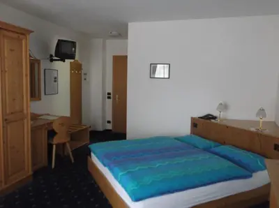 a bedroom with a bed and a desk in it at Hotel Tyrolia in Malga Ciapela