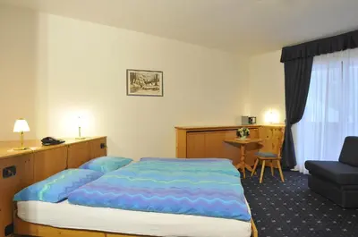 a room with two beds in front of a window at Hotel Tyrolia in Malga Ciapela