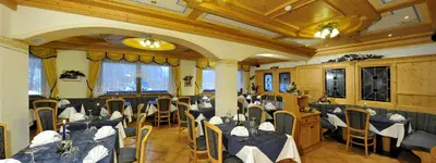 a restaurant with tables and chairs in a room at Hotel Tyrolia in Malga Ciapela