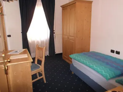 a hotel room with two beds and a window at Hotel Tyrolia in Malga Ciapela