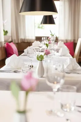 a table with white plates and vases with flowers on it at Hotel Tirolerhof in Rodengo