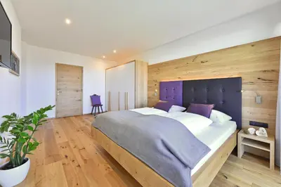 a bedroom with a large bed with a purple headboard at Anger living in Laion