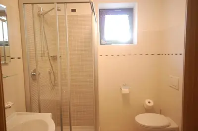 a bathroom with a shower and a toilet and a sink at Garnì Bel Air in Colfosco