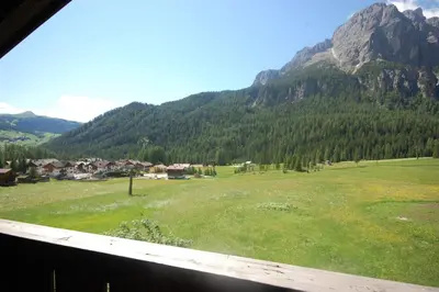 a view of a green field with mountains in the background at Garnì Bel Air in Colfosco