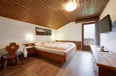 a bedroom with a bed and a desk and a tv at Garnì Bel Air in Colfosco