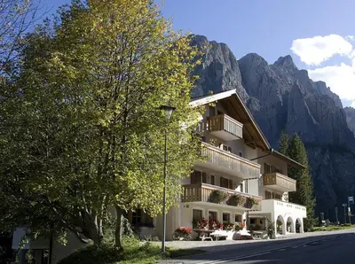 a building with tables and chairs in front of a mountain at Pensione Sellablick in Colfosco