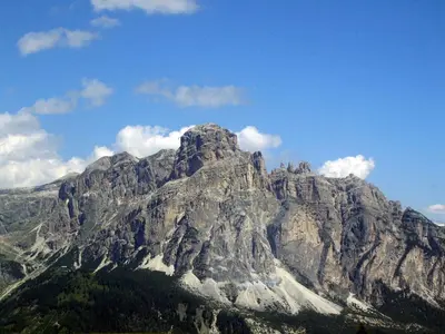 a large rocky mountain with trees in front of it at Pensione Sellablick in Colfosco