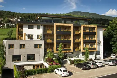 a large building with cars parked in a parking lot at Alpin Hotel Sonnblick in Perca