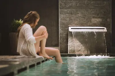 a young woman sitting next to a water fountain at Alpin Hotel Sonnblick in Perca