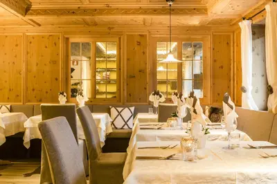 a restaurant with white tables and chairs and windows at Alpin Hotel Sonnblick in Perca