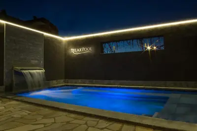 a swimming pool at night with a waterfall at Alpin Hotel Sonnblick in Perca