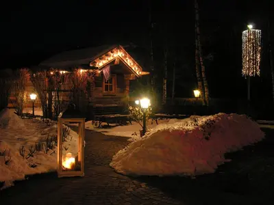 a log cabin with lights in the snow at night at Beauty & Vital Hotel Maria in Carano
