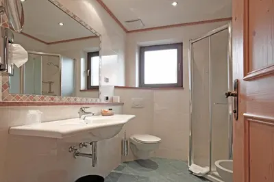 a bathroom with a sink and a toilet and a mirror at Beauty & Vital Hotel Maria in Carano
