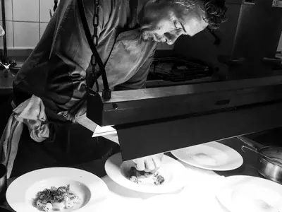 a man standing in a kitchen preparing plates of food at Hotel Stefanshof in Plaus