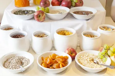 a table topped with white bowls filled with different types of food at Hotel Stefanshof in Plaus