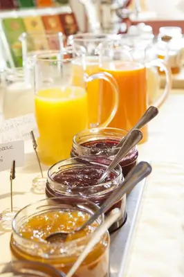 a table with glasses of orange juice and jars of preserves at Hotel Stefanshof in Plaus