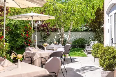 a patio with tables and chairs and an umbrella at Hotel Rosskopf in Vipiteno