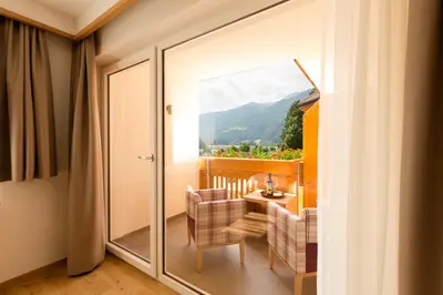 a room with a balcony with a table and chairs at Hotel Rosskopf in Vipiteno