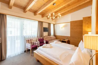 a hotel room with a bed and a couch at Hotel Rosskopf in Vipiteno