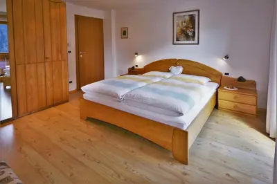 a bed with yellow striped sheets in a bedroom at Apartment Larjëi in Ortisei
