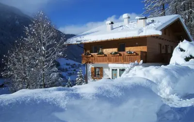 a log cabin in the snow with a mountain at Apartment Larjëi in Ortisei