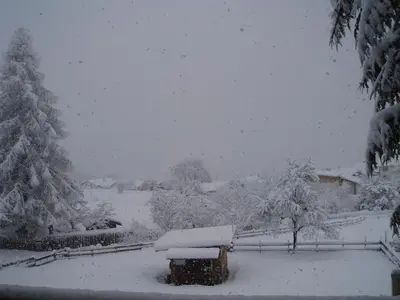 a snow covered yard with a bench and trees at Dillerhof in Laion