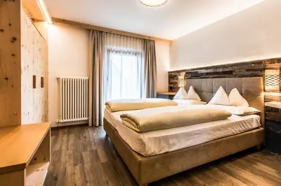 a large bedroom with two beds and a window at Pensione Camoscio in La Villa