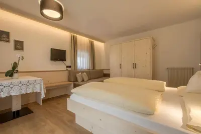 a bedroom with a large bed and a table at Pensione Camoscio in La Villa
