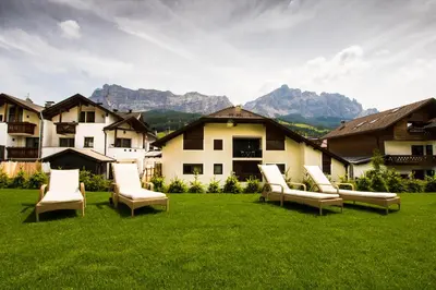 a group of chairs on a lawn with mountains in the background at Pensione Camoscio in La Villa