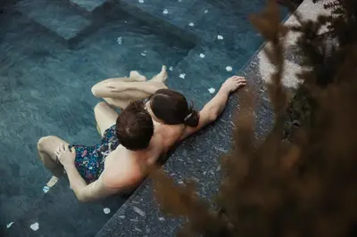 a man and woman sitting in a swimming pool at Pensione Camoscio in La Villa