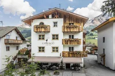 a large white building with wooden balconies in a village at Pensione Camoscio in La Villa