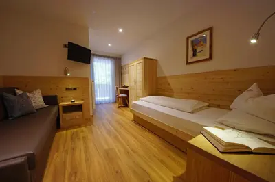 a hotel room with two beds and a television at Garnì Tofana in Corvara in Badia