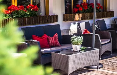 a patio with couches and a table with red pillows at Garnì Tofana in Corvara in Badia