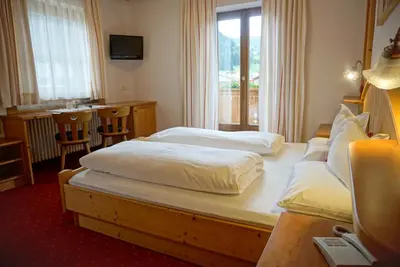 a hotel room with two beds and a couch at Garnì Tofana in Corvara in Badia