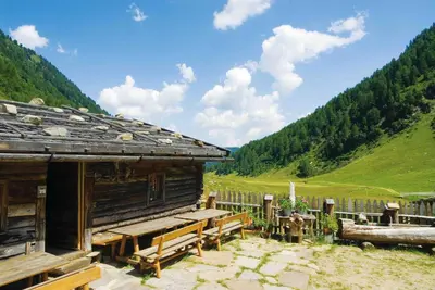 a cabin in the mountains with a table and benches at Naturhotel Rainer in Racines