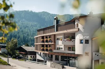 a building with a balcony with flowers on it at Plan Murin - Authentic Dolomites Hotel in La Valle