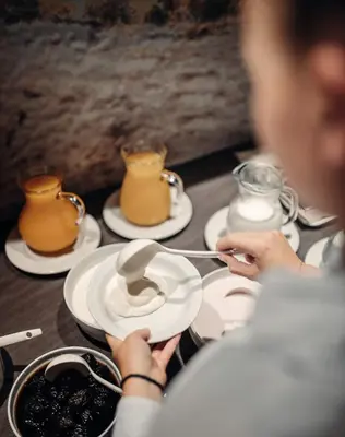 a person sitting at a table with plates of food at Plan Murin - Authentic Dolomites Hotel in La Valle
