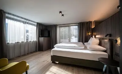 a hotel room with two beds and a television at Plan Murin - Authentic Dolomites Hotel in La Valle