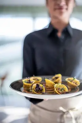 a man holding a tray of food on a plate at Plan Murin - Authentic Dolomites Hotel in La Valle