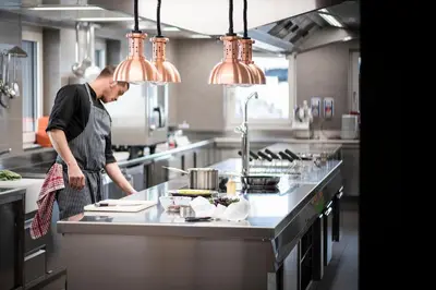 a man standing in a kitchen preparing food at Plan Murin - Authentic Dolomites Hotel in La Valle